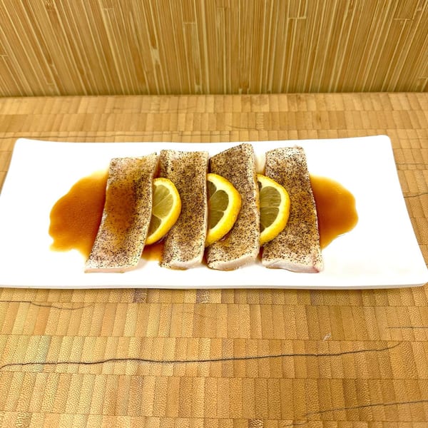 Sawara Sushi's seared fish slices with lemon and sauce on a white rectangular plate.