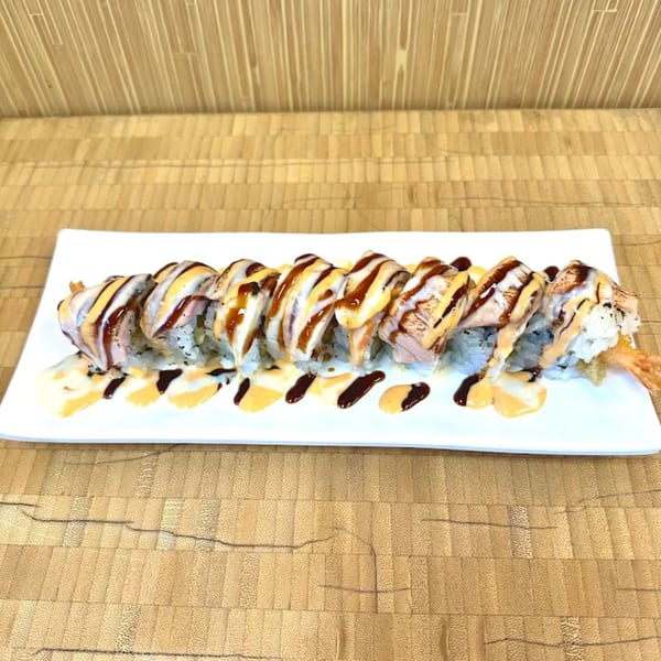 Sawara Sushi's long sushi roll with salmon, white sauce, and dark sauce on a white plate.