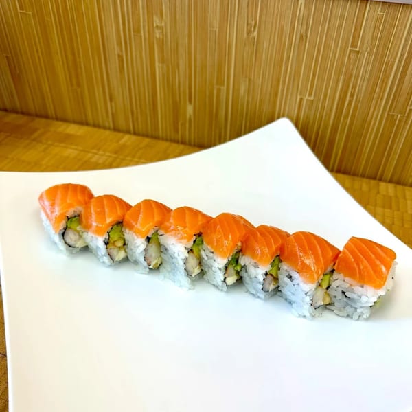 Sawara Sushi's salmon rolls with avocado and shrimp on a white plate against a bamboo background.